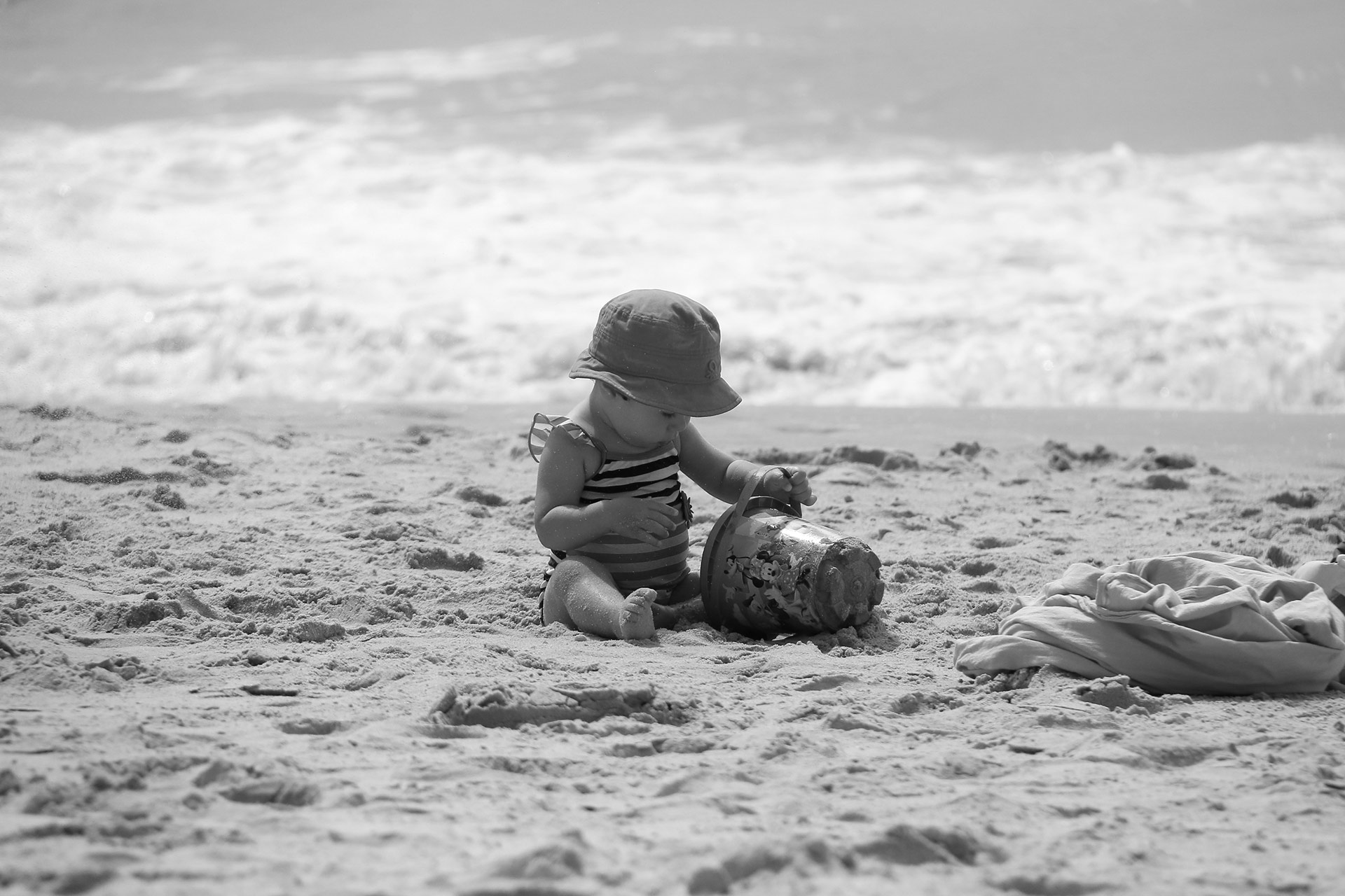 little girl on the beach with a bucket